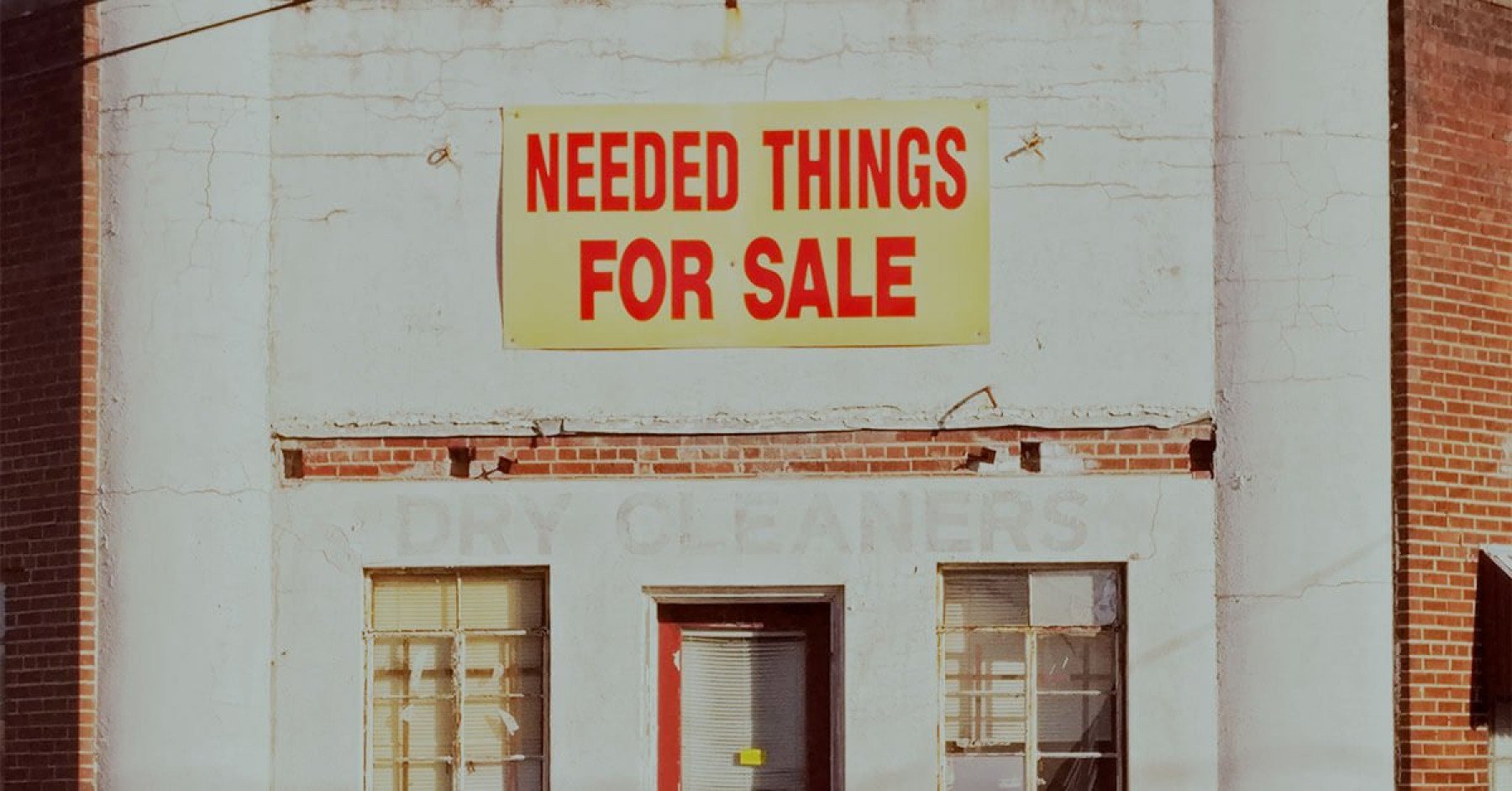 Bild på en tegelfast med en skylt där det står Needed things for sale