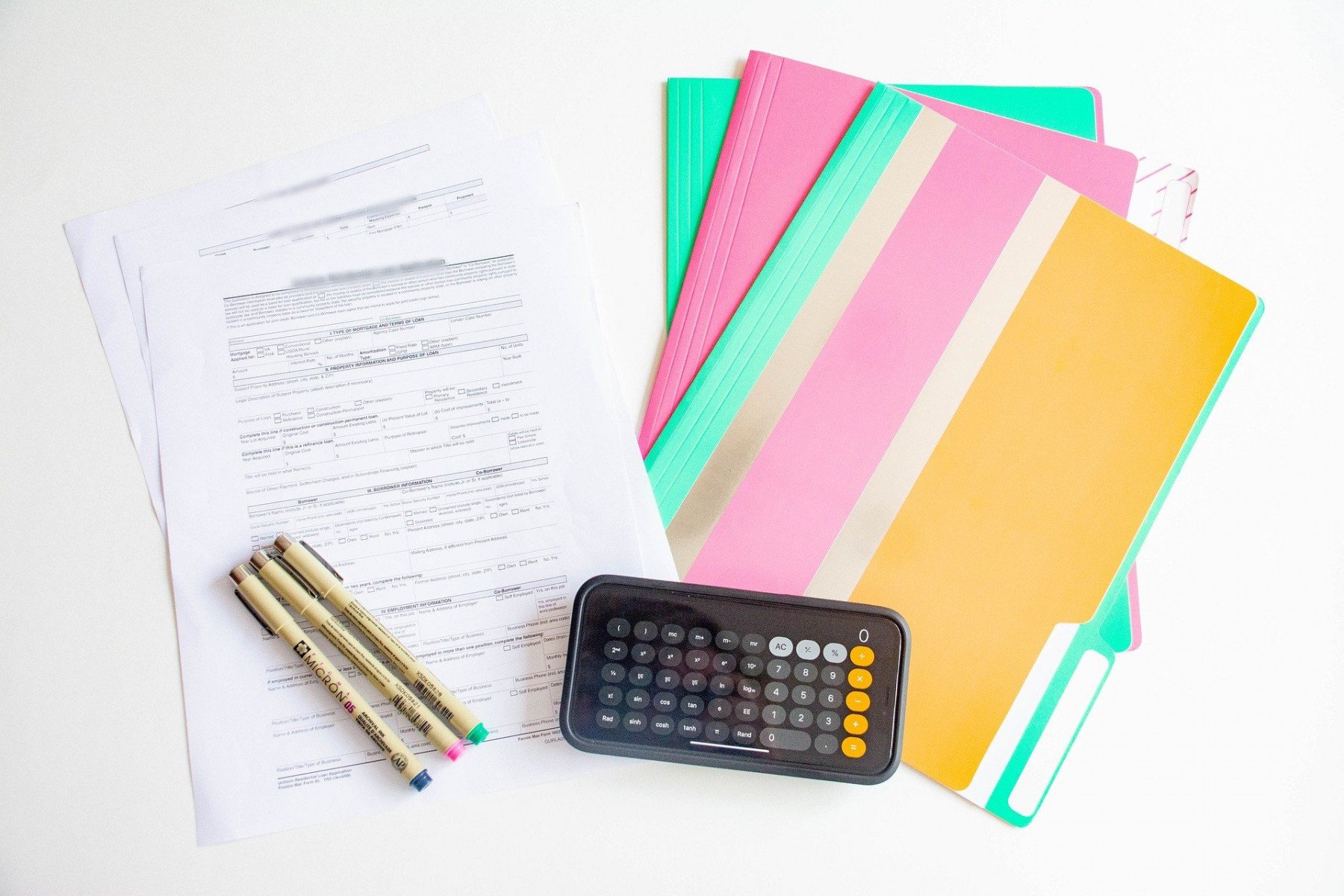 Avtal, pärmar och pennor ligger på ett bord med en mobil