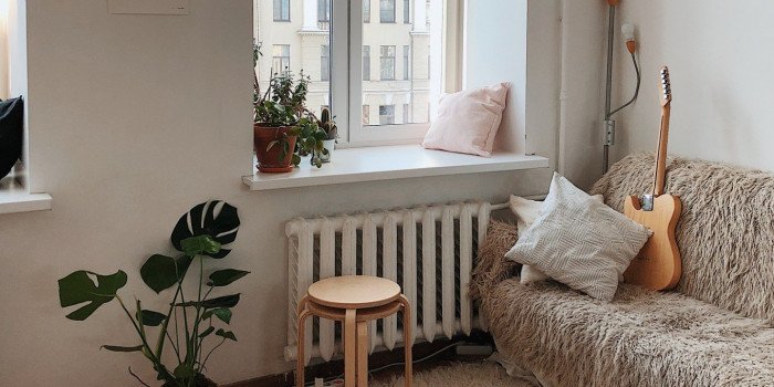 Bild inuti en lägenhet med soffa, gitarr och pallar