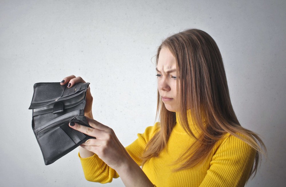 Kvinna med tom plånbok – symboliserar lån för skuldsatta