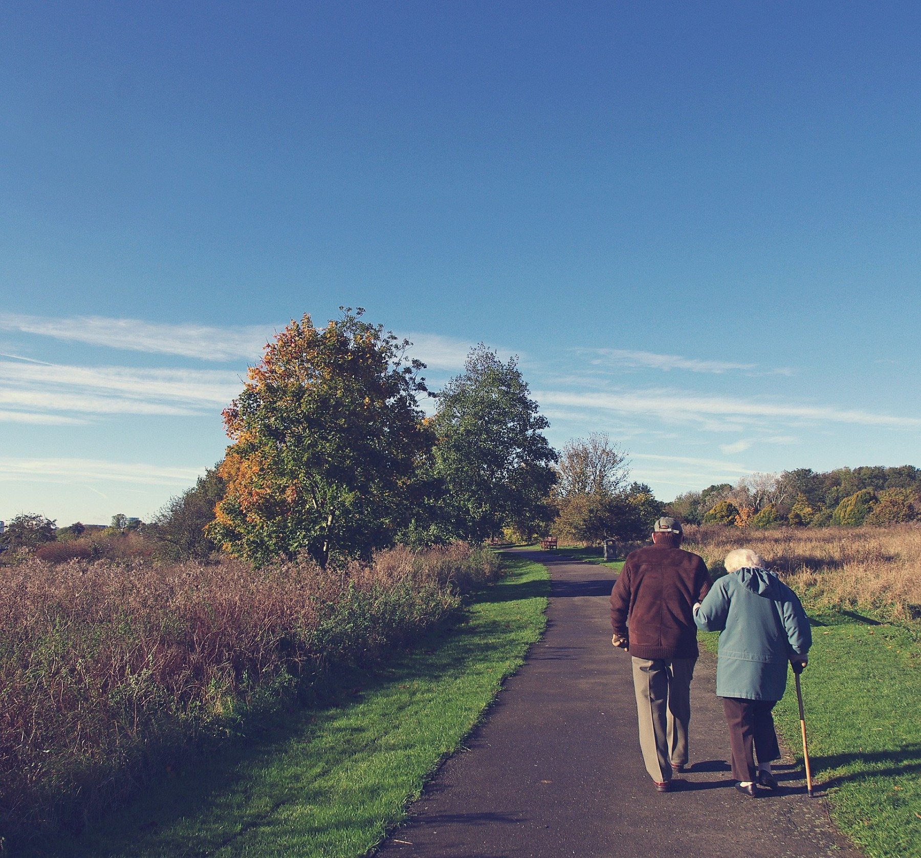 Två äldre personer går på en grusväg i naturen