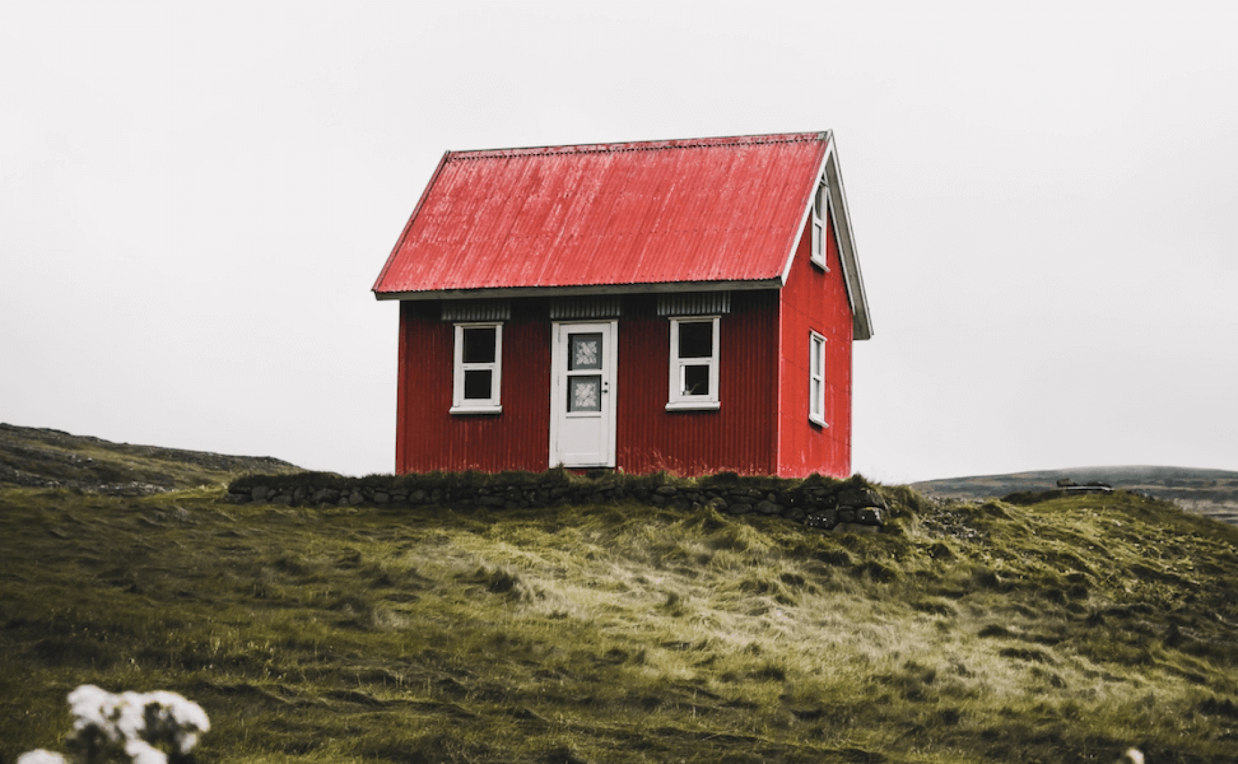 Rött hus med vita knutar i öde landskap