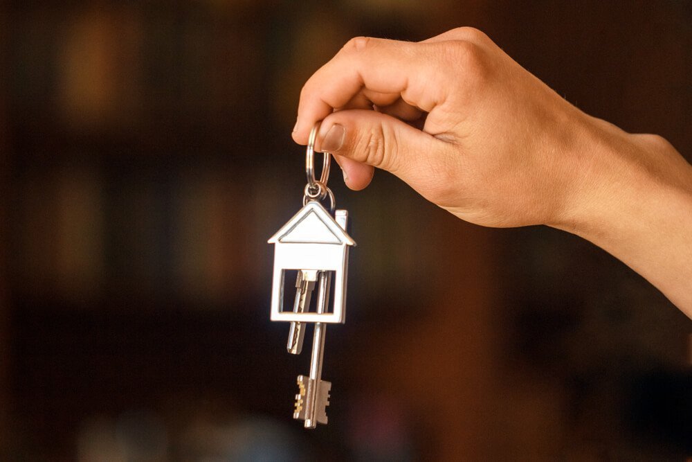 Person som håller upp nycklar med ett hus på