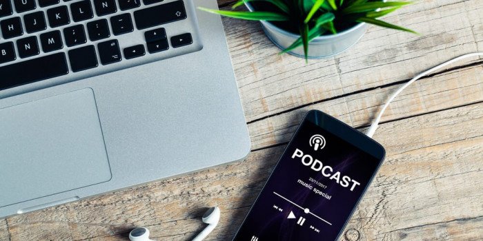 Bord med en Mac-dator och en iPhone med texten Podcast på