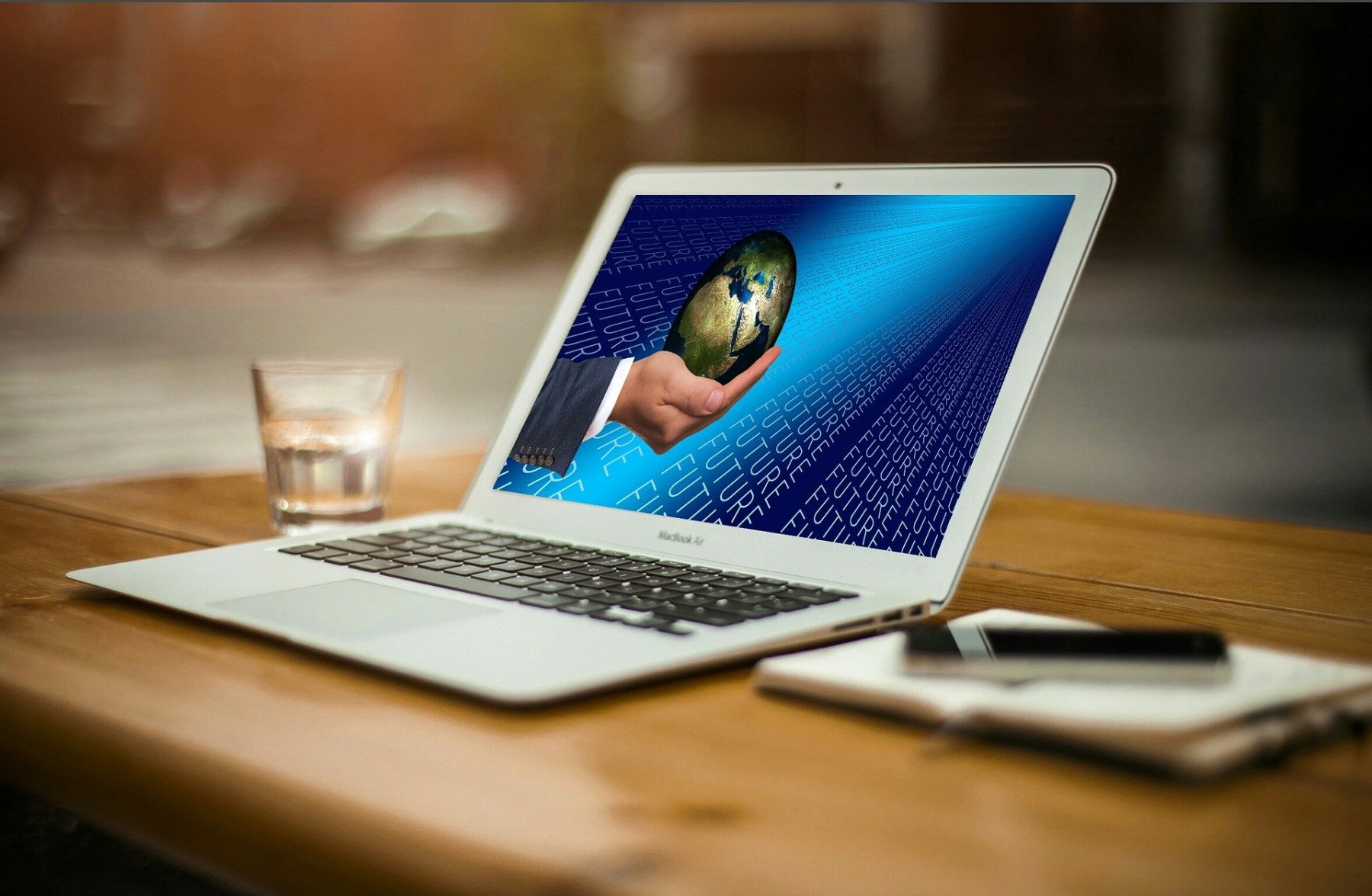 Laptop uppställd på ett bord med en skärmsläckare som föreställer en hand som håller i en jordglob