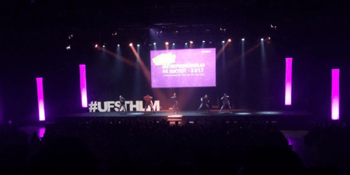 UF Sthlm står på en scen och håller i en presentation