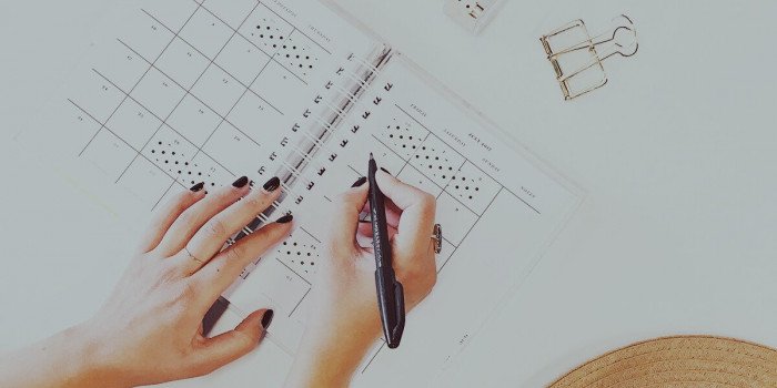 Händer som skriver i en kalender.